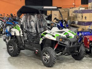 A green and white four-wheeler parked in a garage.