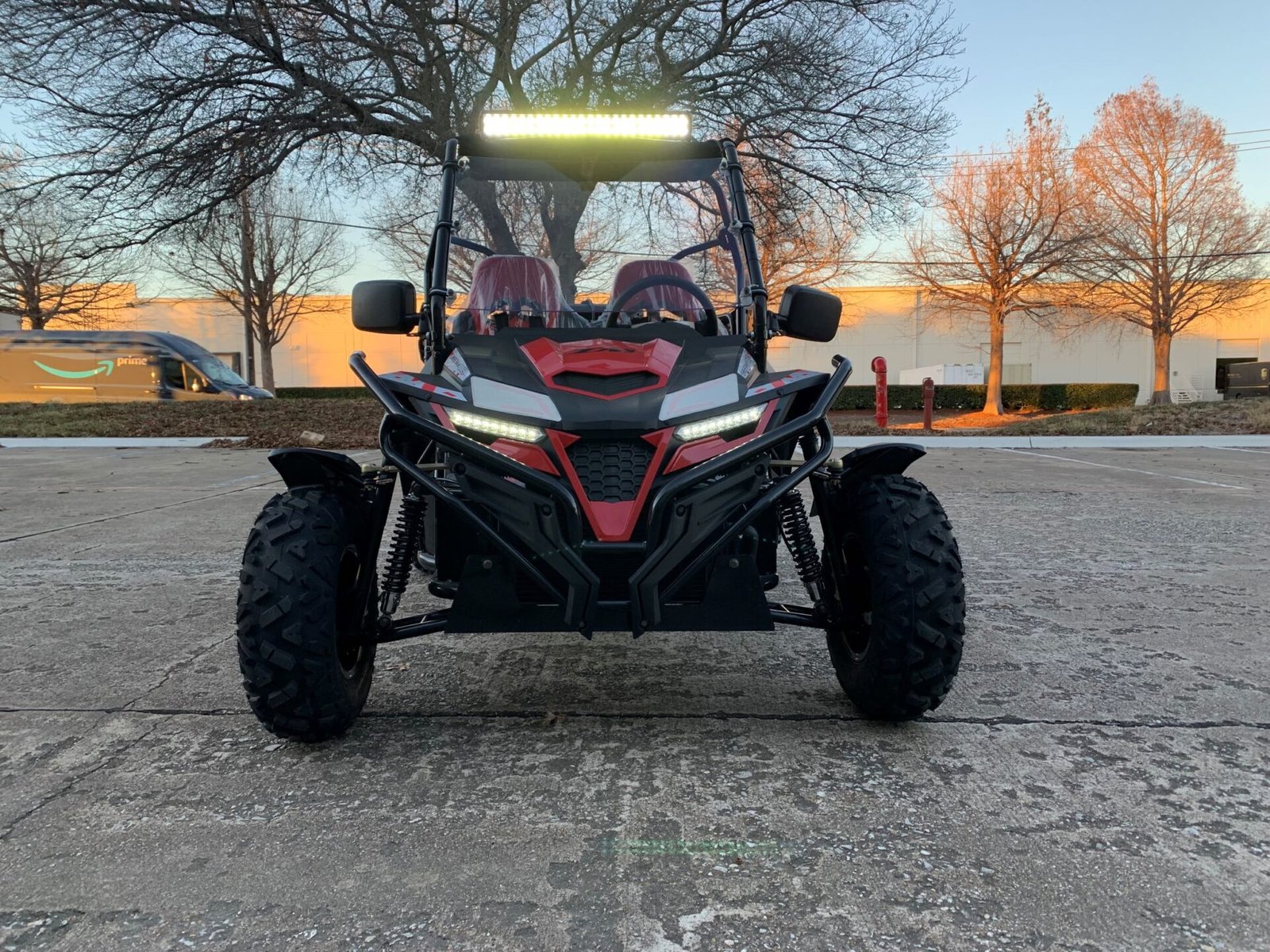 A red and black buggy parked in the middle of a parking lot.