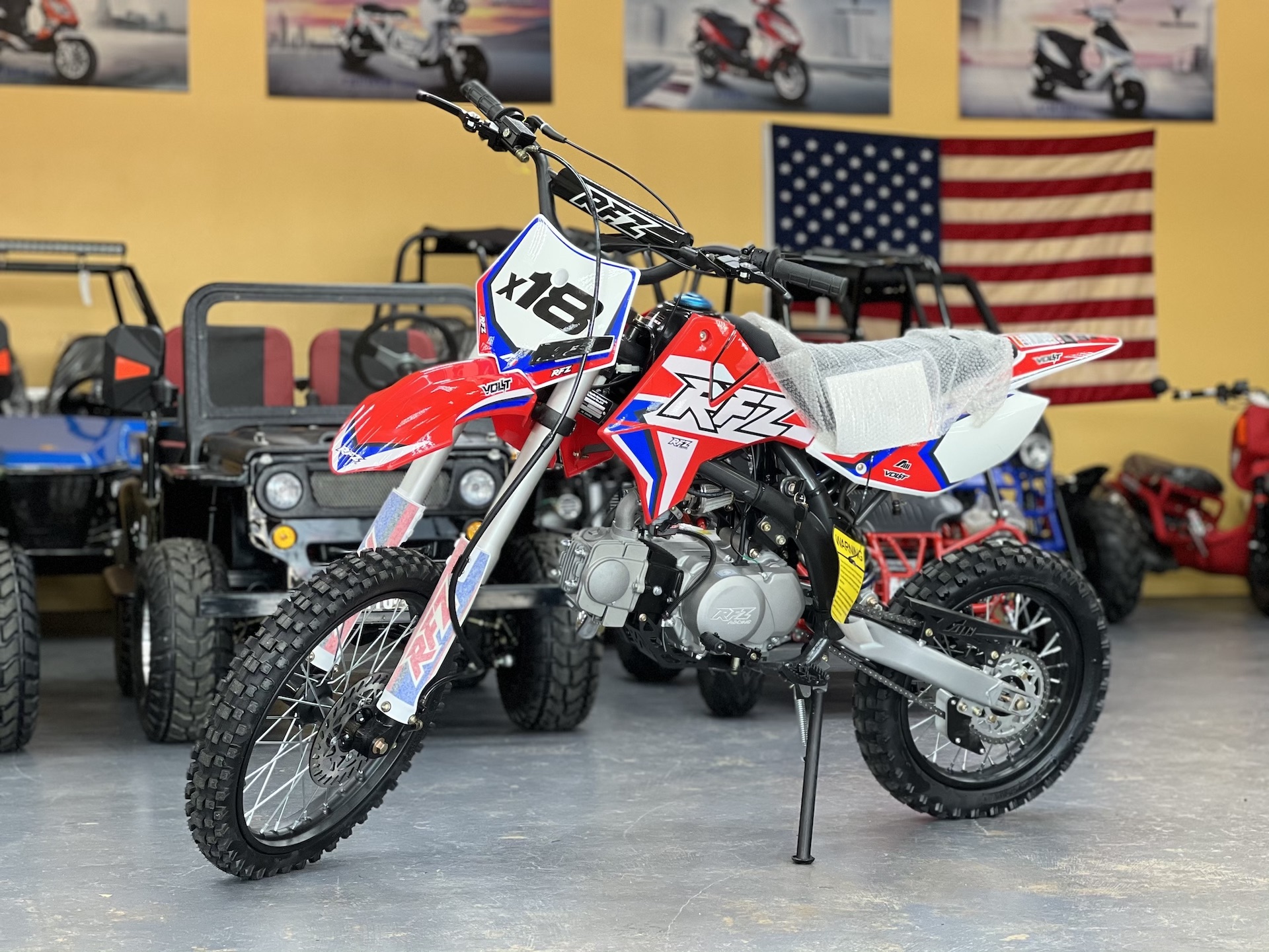A red and white dirt bike parked in front of an american flag.