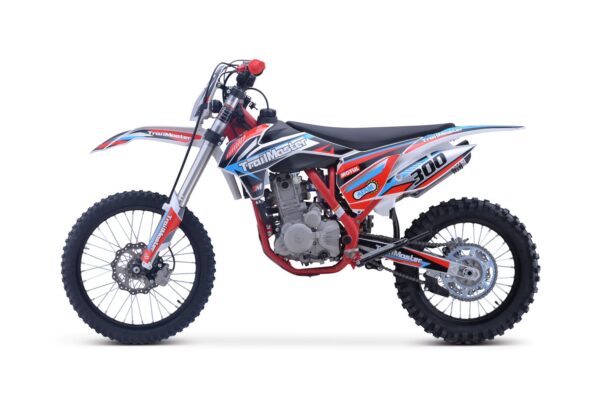A red, white and blue dirt bike is parked on the ground.