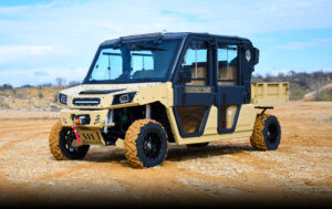 A tan and black utility vehicle parked in the sand.