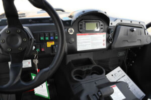 A dashboard of an off road vehicle with the steering wheel and controls.