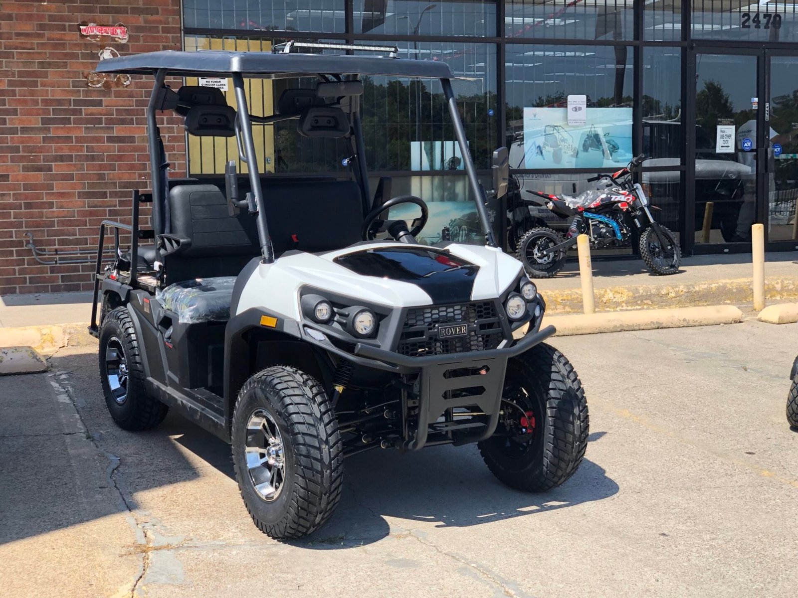 A white and black golf cart parked in front of a building.