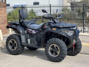 A black four-wheeler parked in front of a fence.