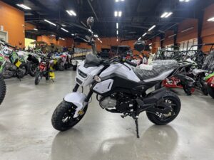 A white motorcycle parked in a room with lots of motorcycles.