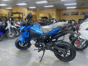 A blue motorcycle parked in a room with other motorcycles.
